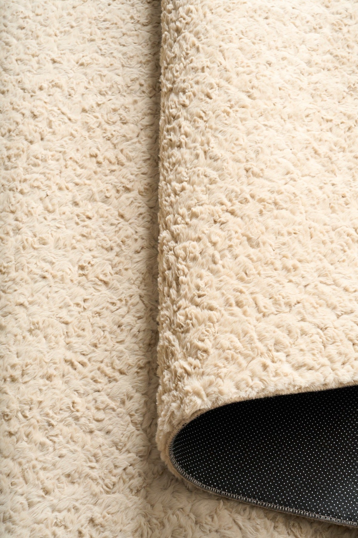 Cream shag rug seam detail with dark backing edge