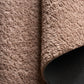 Taupe sherpa rug with curled edge and textured pile, corner view with backing