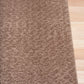 Taupe shaggy sherpa rug with thick plush pile and visible backing at corner
