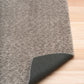 Gray shaggy rug corner with dark woven backing underside