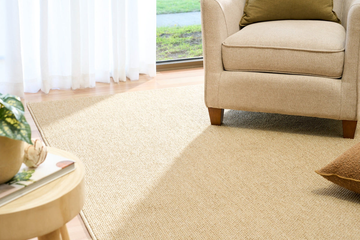 Beige area rug on hardwood floor, textured looped surface