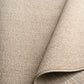Light brown textured area rug corner with rounded underlayer edge