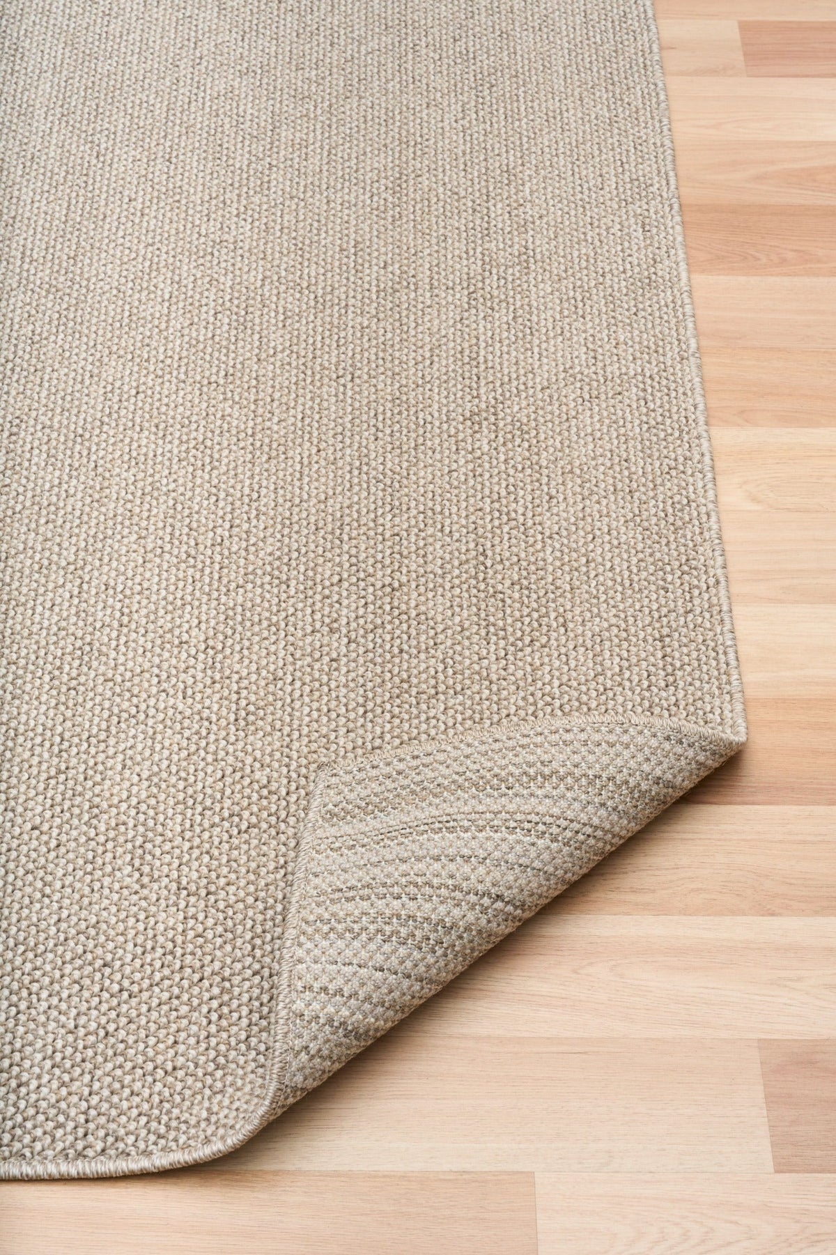 Light brown textured area rug with woven border and corner detail