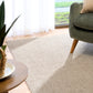 Light brown textured area rug with corner placement and sofa leg visible