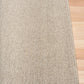 Light brown textured area rug edge with tight flat border stitching