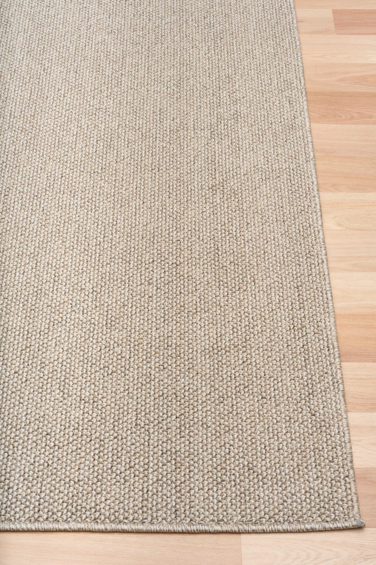 Light brown textured area rug edge with tight flat border stitching