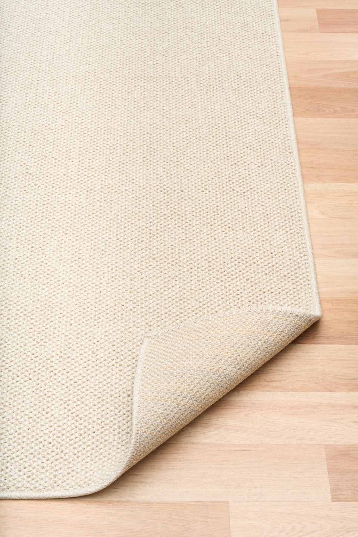 Cream woven area rug with short textured pile and neatly finished edge