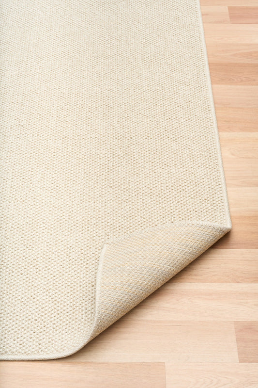 Cream woven area rug with short textured pile and neatly finished edge