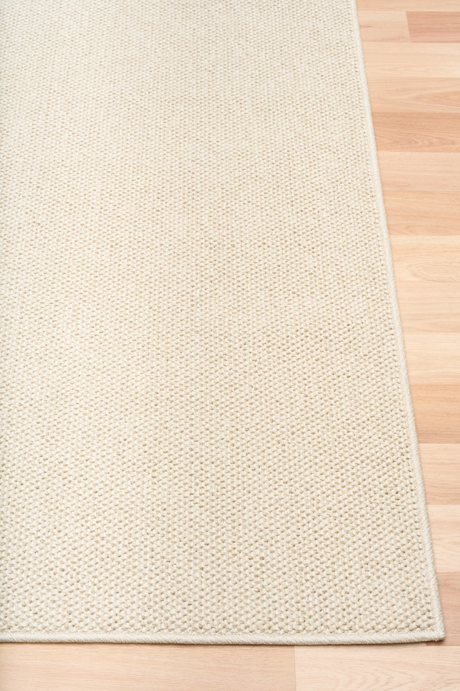 Cream woven area rug with squared border and tight, textured surface