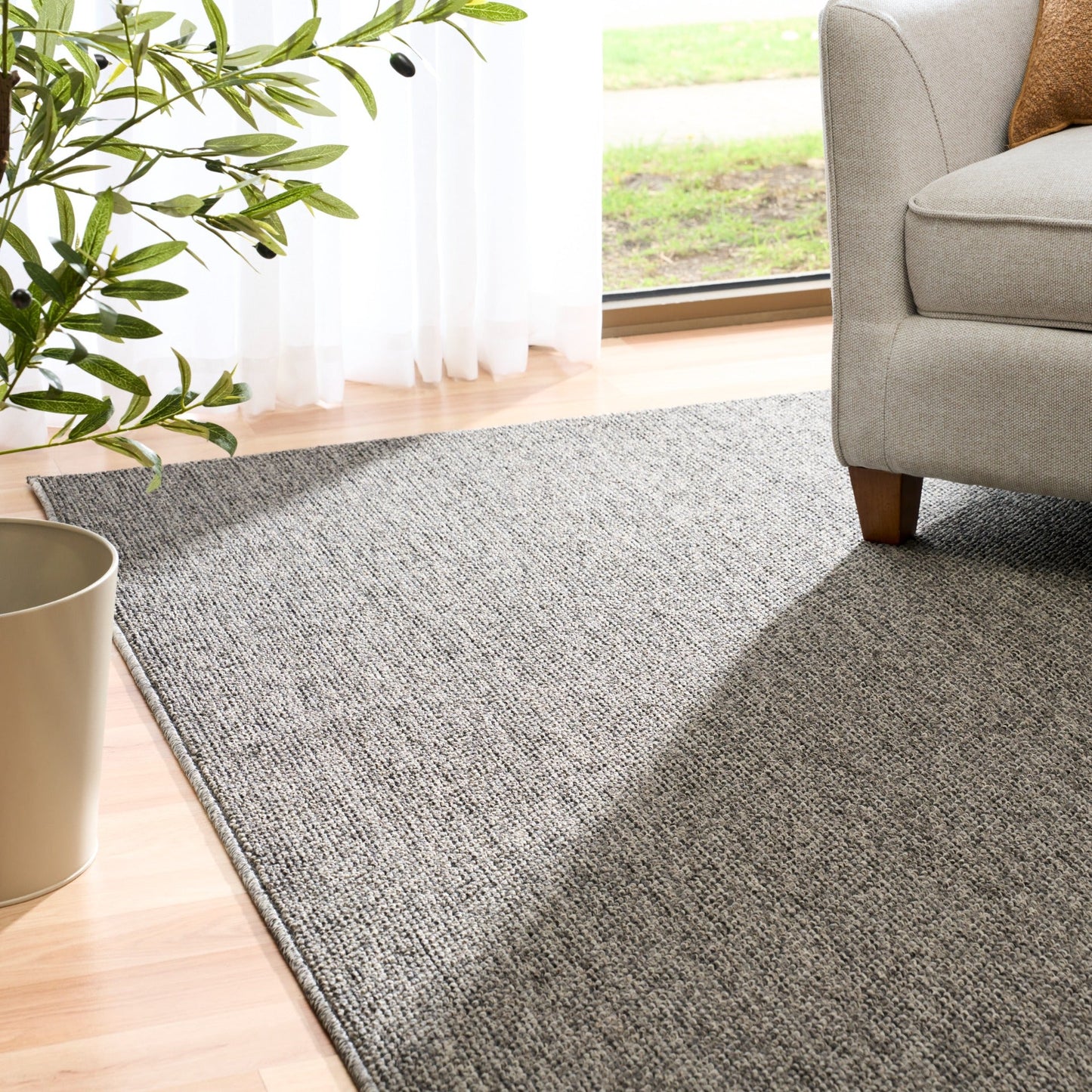 Grey woven area rug corner on light wood floor