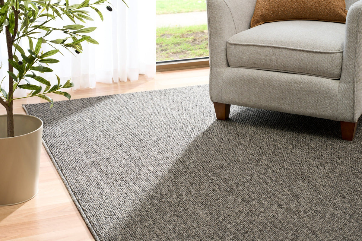 Grey woven area rug on light wood floor