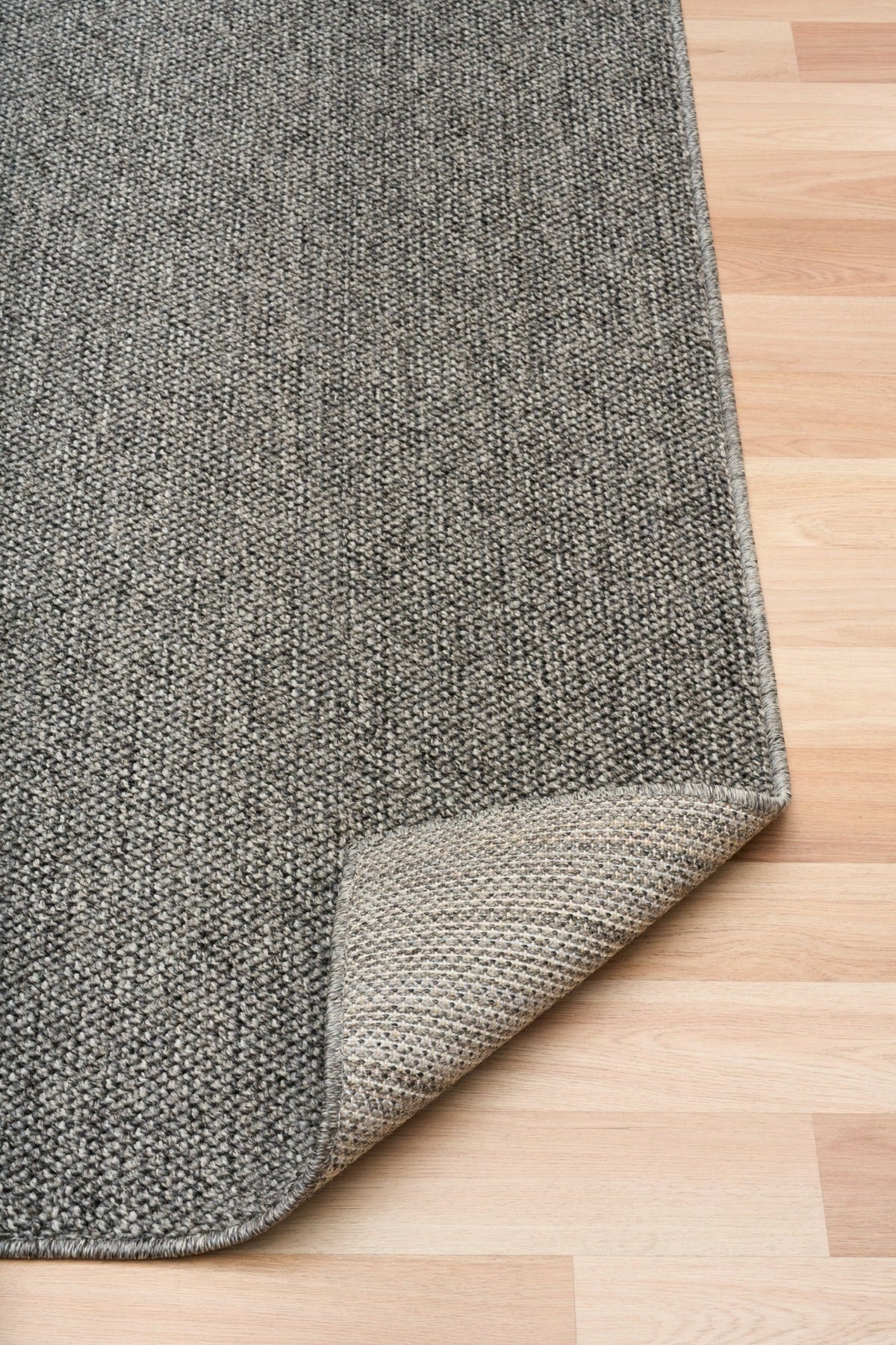 Grey area rug with light stitched edge on the corner