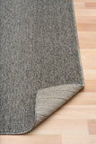 Grey area rug with light stitched edge on the corner