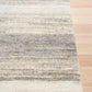 Bone grey striped area rug corner with bound edge on hardwood floor