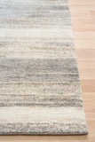 Bone grey striped area rug corner with bound edge on hardwood floor