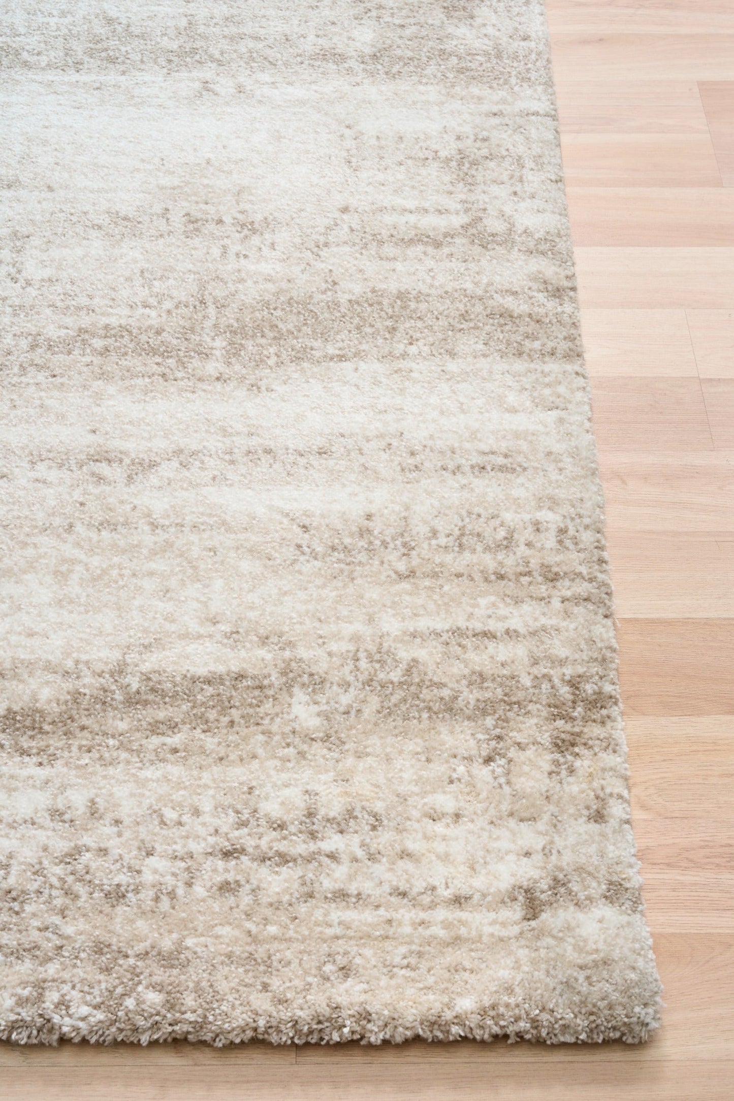 Bone cream area rug corner with short textured pile and distressed pattern