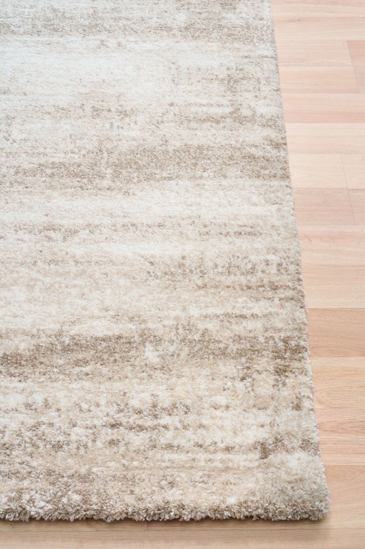 Bone cream area rug corner with short textured pile and distressed pattern