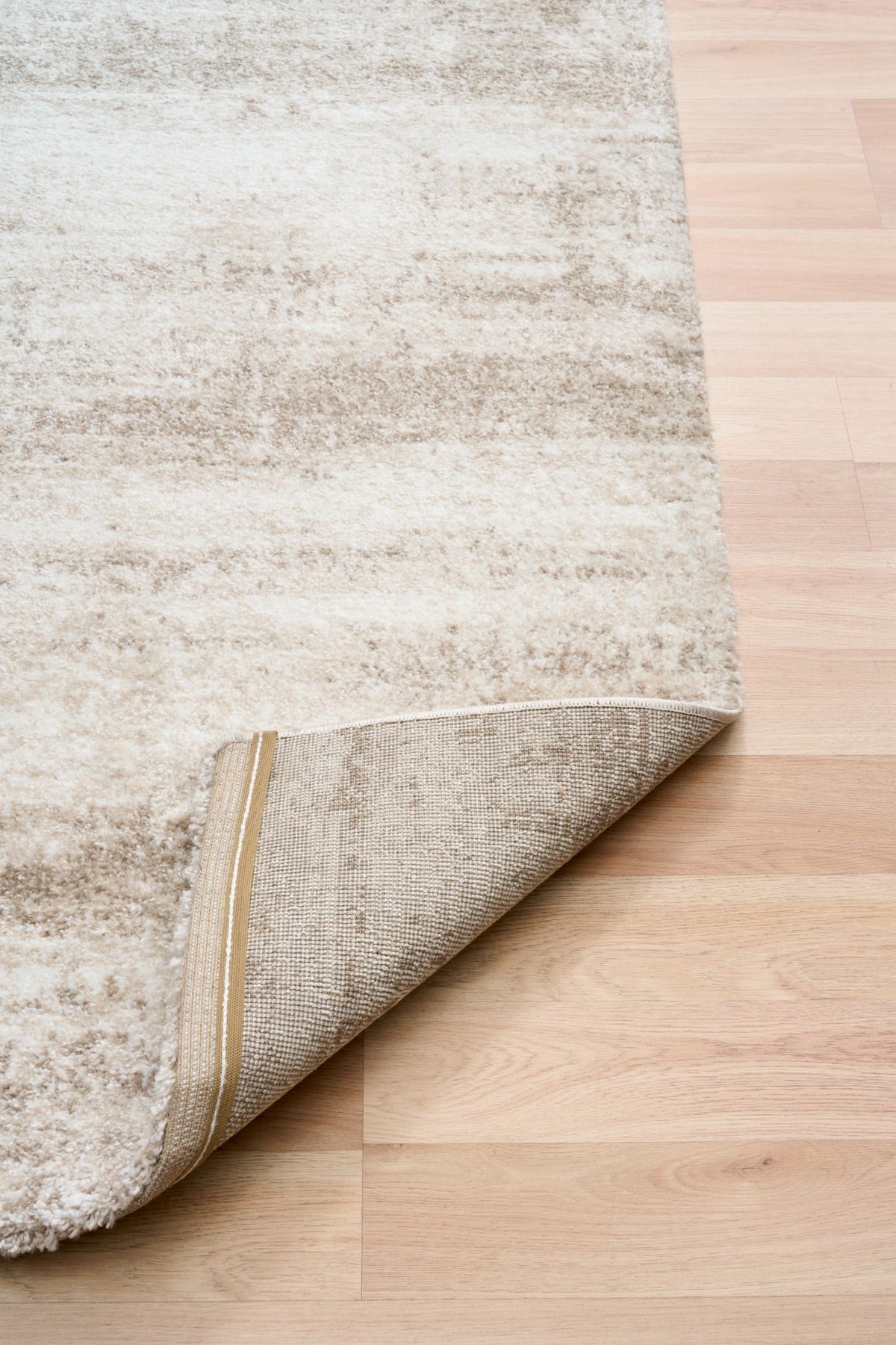 Bone cream area rug edge with beige binding and distressed texture pattern