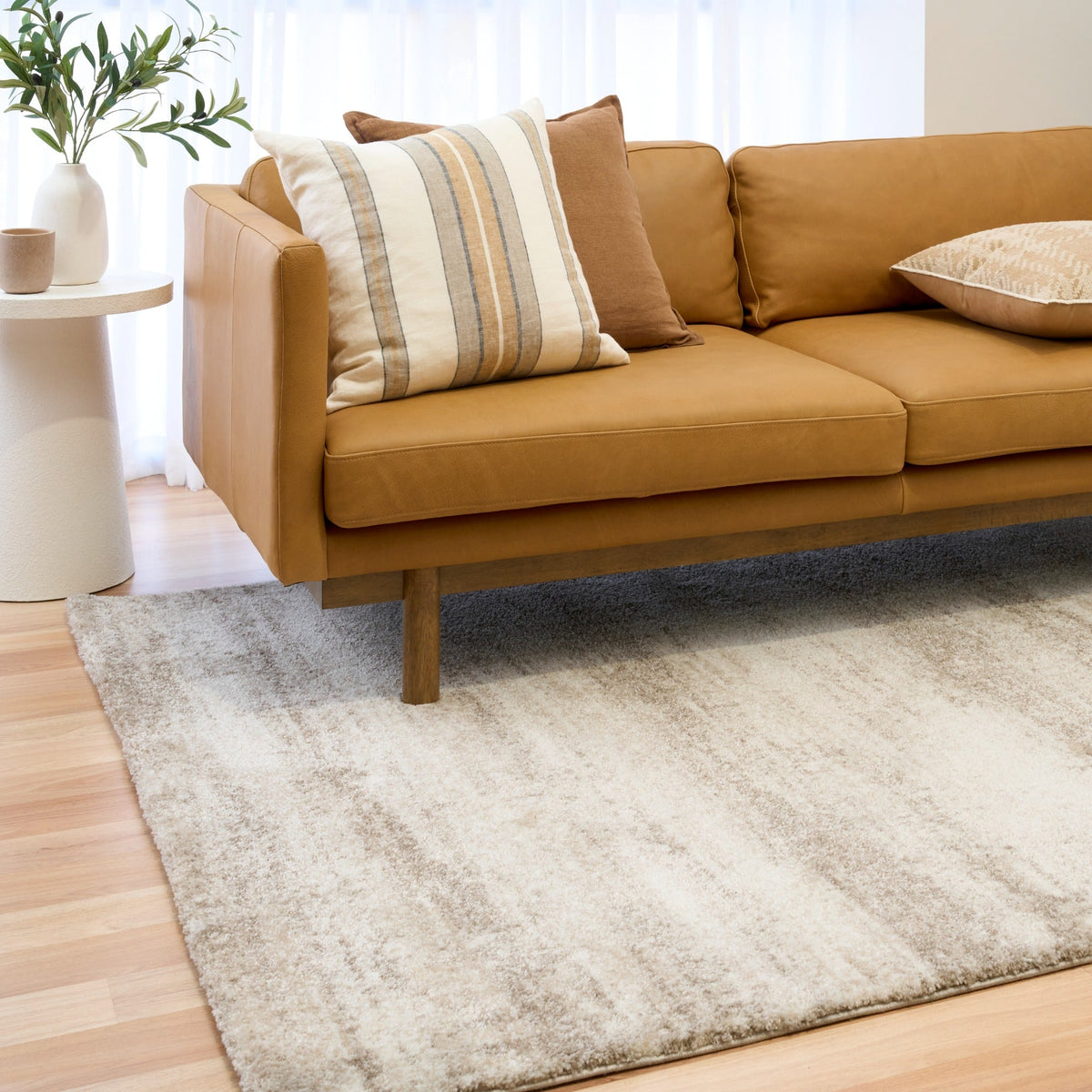 Bone cream area rug with distressed texture pattern beside a tan sofa