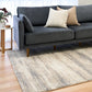 Grey and cream abstract area rug alongside dark sofa, low-pile woven texture