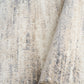 Grey and cream abstract area rug close-up with rolled edge and low pile texture