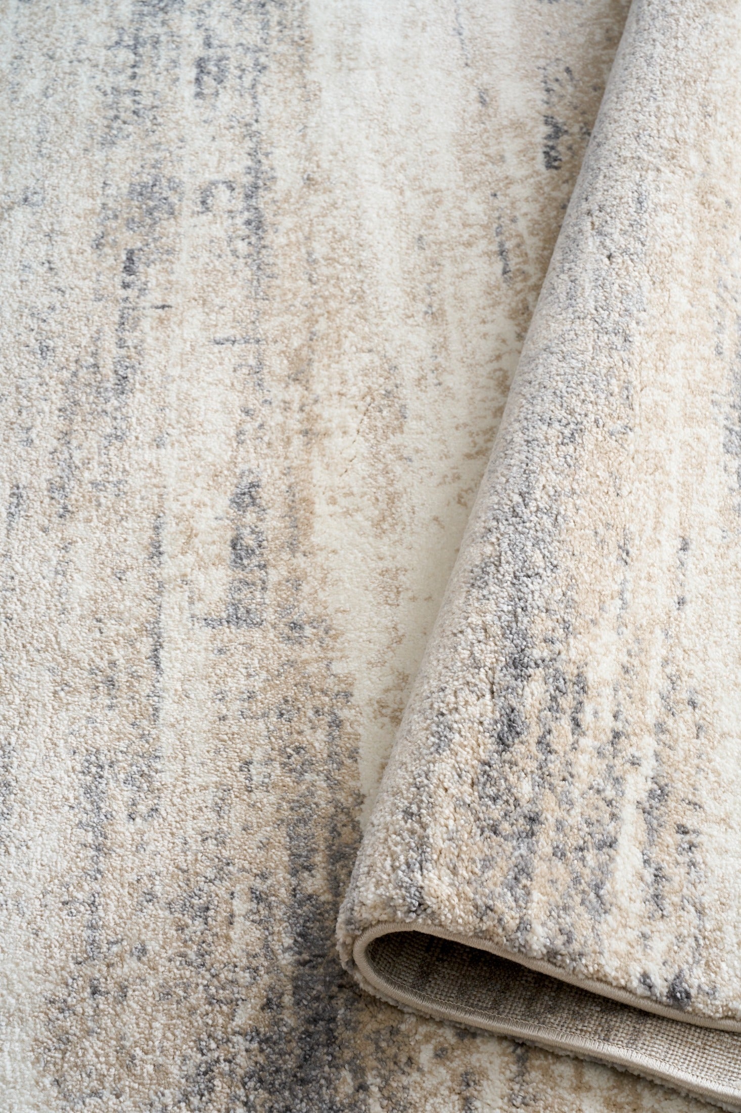 Grey and cream abstract area rug close-up with rolled edge and low pile texture