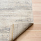 Grey and cream abstract area rug rolled back corner, showing short textured pile