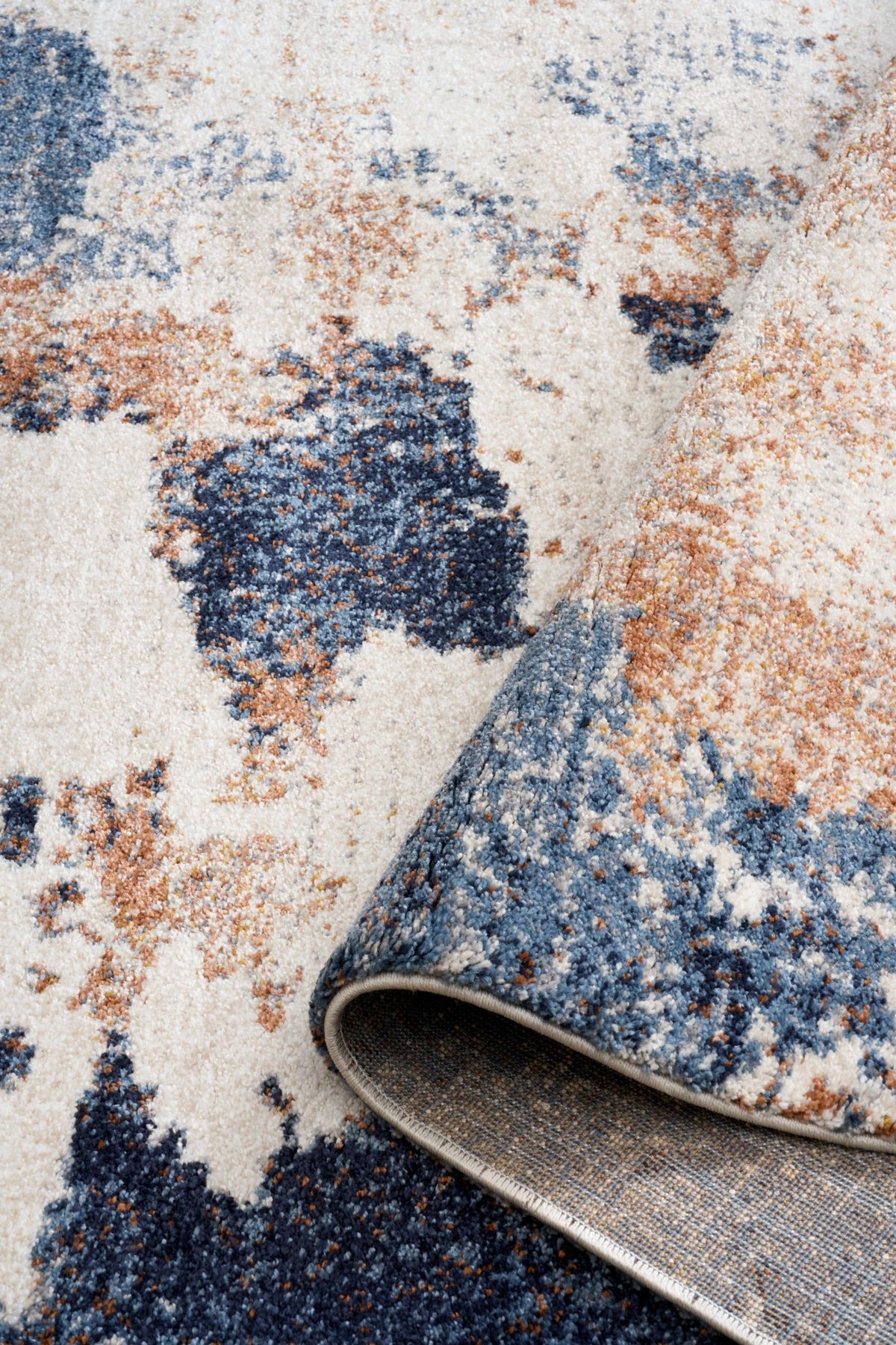 Close-up of rug pile texture with distressed cream, navy blue, and rust speckles