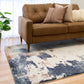 Rectangular area rug with distressed cream, navy blue, and rust abstract pattern on floor