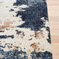 Rectangular rug featuring distressed cream background with dark blue and rust abstract blocks