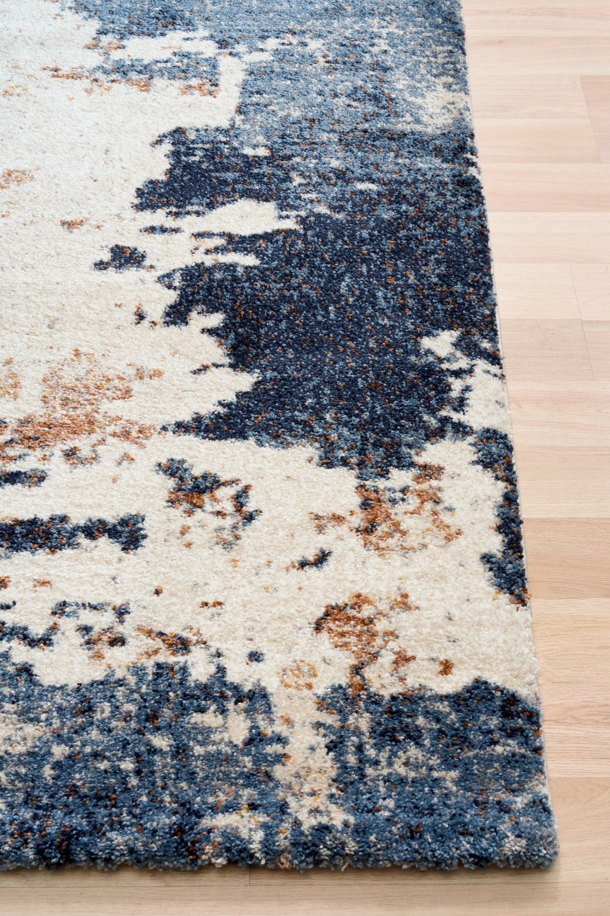 Rectangular rug featuring distressed cream background with dark blue and rust abstract blocks