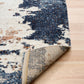 Corner view of rectangular rug with cream and blue distressed pattern; woven backing visible