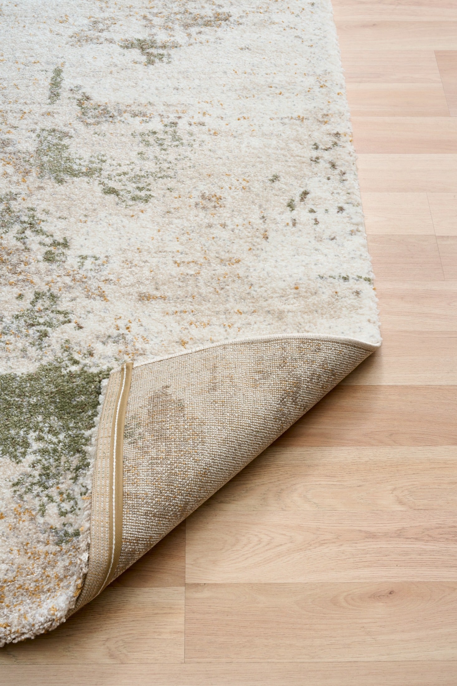 Green and cream abstract area rug with visible stitched border and rolled edge
