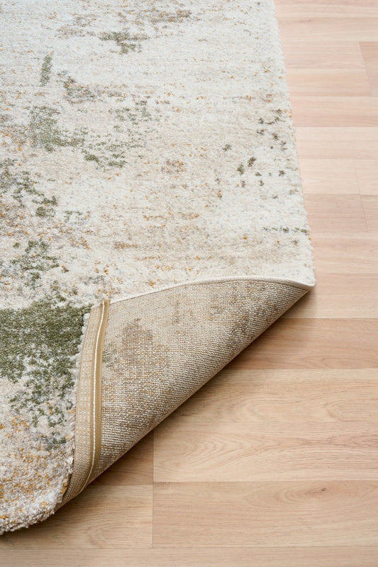 Green and cream abstract area rug with visible stitched border and rolled edge