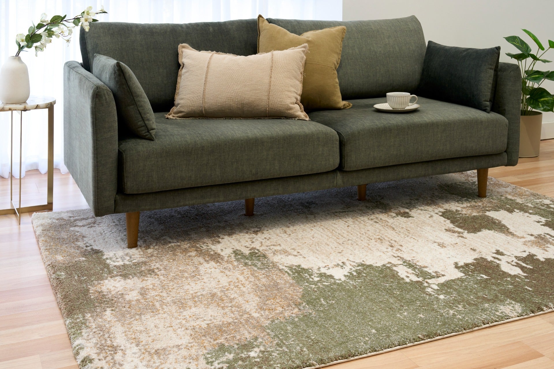 Green and cream abstract area rug on hardwood floor, distressed mottled pattern