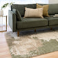 Green and cream abstract area rug with corner visible on hardwood floor