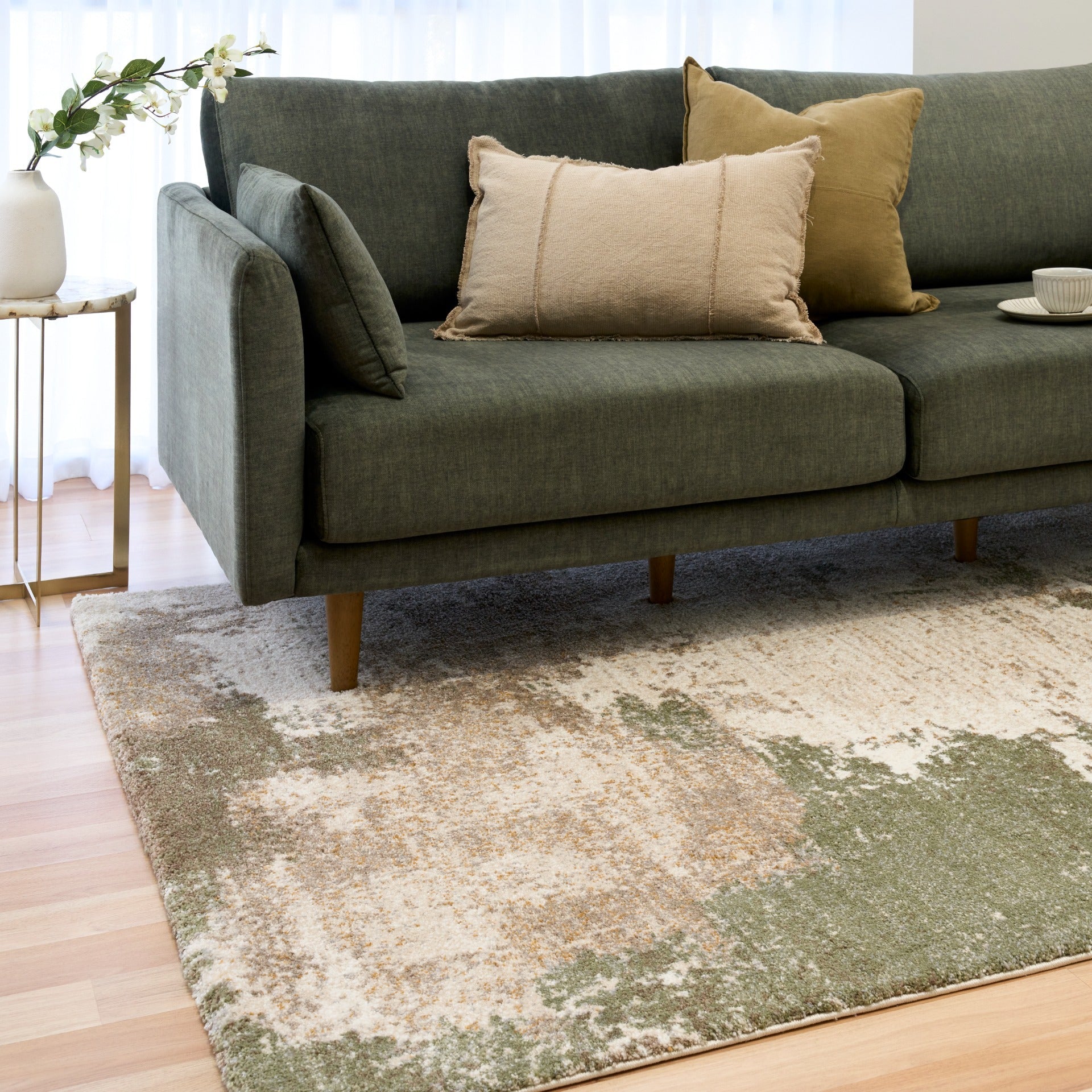 Green and cream abstract area rug with corner visible on hardwood floor
