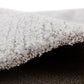 Grey rug edge with fluffy loop pile and visible underside thickness