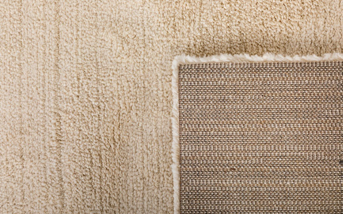 Ivory area rug edge with woven binding and textured pile border