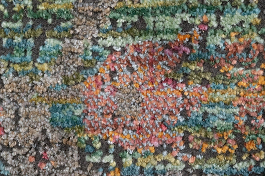 Textured abstract rug surface detail with teal, coral, mustard, and gray fibers