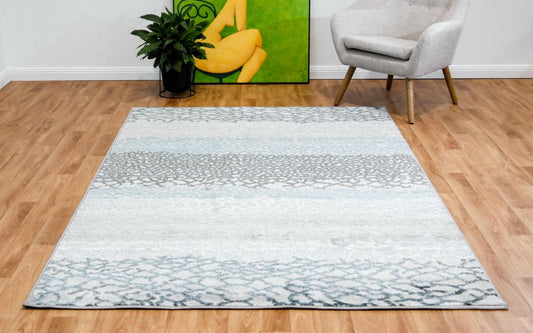 Grey and teal abstract geometric area rug with central motif and border.