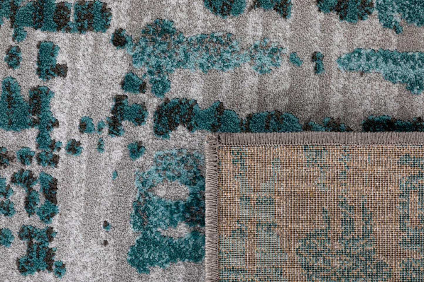 Abstract grey-and-teal area rug corner with border and flat-woven trim