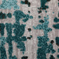 Light grey rug with teal-blue abstract shapes and textured look