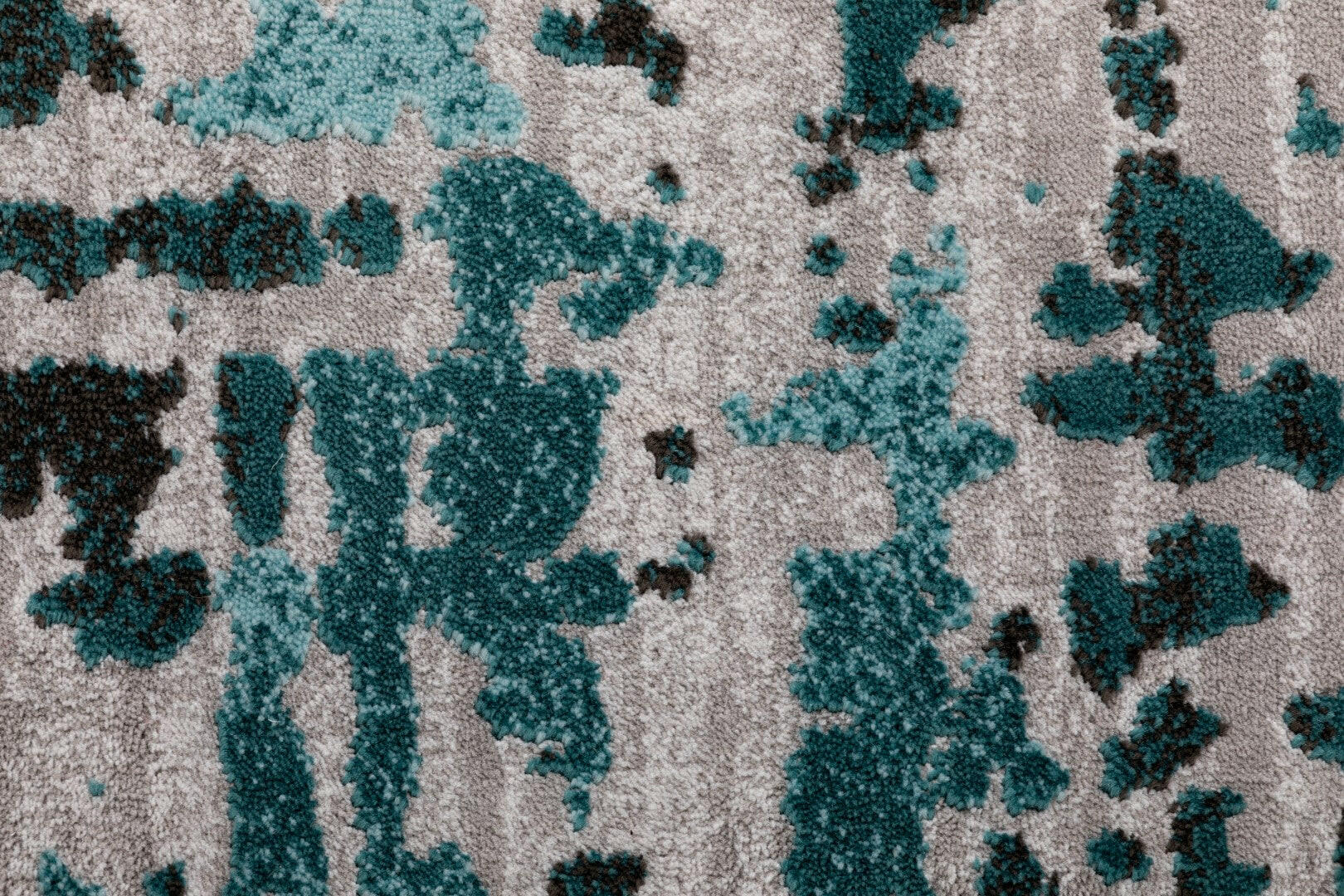 Light grey rug with teal-blue abstract shapes and textured look