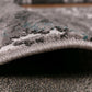 Rolled edge of gray and white area rug with thick textured pile and trim