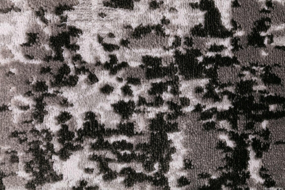 Close-up of abstract rug texture with dark and light mottled speckle design.