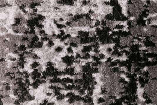Close-up of abstract rug texture with dark and light mottled speckle design.