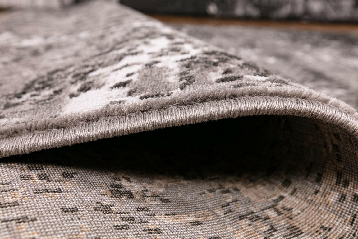 Rug pile edge detail showing curved binding and thick low-profile construction.