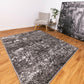 Abstract area rug with dark gray and light speckled pattern, rectangular border edges.