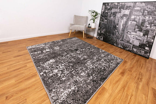 Abstract area rug with dark gray and light speckled pattern, rectangular border edges.